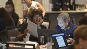 school librarians sit around a table with laptops and books working together