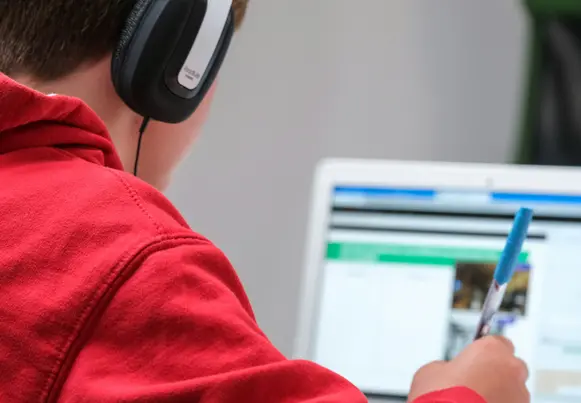 Young person in red hoodie studying computer screen