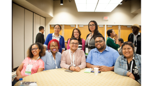 Engage with Colleagues with Core. A group of 6 women and 2 men posed around a table smiling