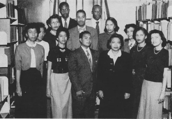 Black and white image of group of men and women standing amidst library shelves