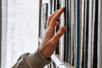 Person's hand searching stacks for a specific book