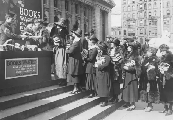 Drive for books for fighters. Photo shows a number of girls each with a pile of books wending her way into the Public Library Building, New York, where they left books to be sent to camps. This campaign for books was started by the American Library Association. March 18, 1918