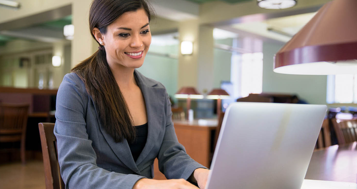 A woman applying for a job online on her laptop in the library