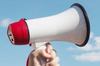 Hand holding a megaphone to the sky