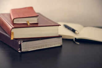 Stack of books with one open and a pen