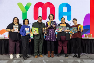 Group of people holding books in front of backdrop that says YMA